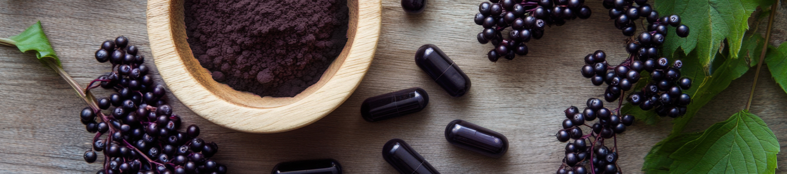 Elderberry capsules next to elderberry powder in a brown bowl and a bushel of elderberries.