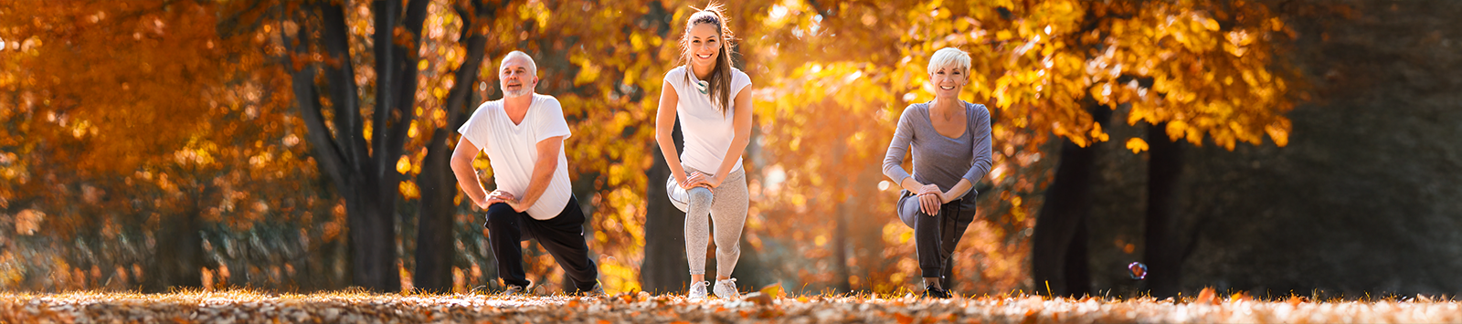 One elderly man, one elderly woman, and one middle-age woman stretch before a run.